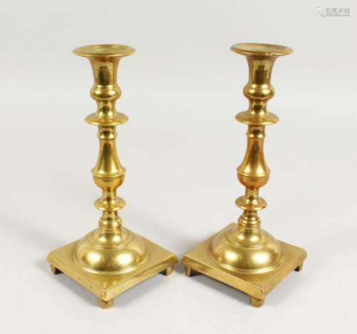 A PAIR OF HEAVY BRASS CANDLESTICKS, with square bases.