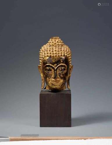 A Thai lacquered and gilded bronze head of a Buddha. 19th centuryThe oval head with a [...]