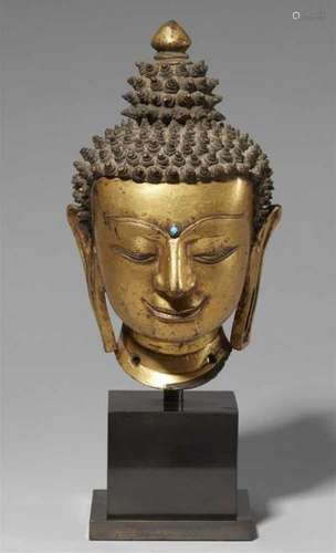 A precious Tibetan gilt bronze head of a Buddha. 14th/15th centuryThe serene face [...]