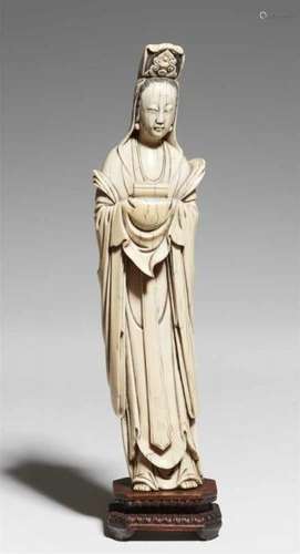 An ivory figure of a Guanyin. Late 19th centuryStanding and and supporting a scroll [...]