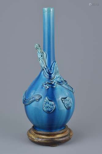 Porcelain blue ground bottle vase wrapped with a molded dragon on a Wooden Stand, 32cms high