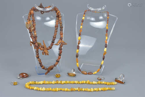 Two amber beaded necklaces together with five white metal and amber rings together with a white meta