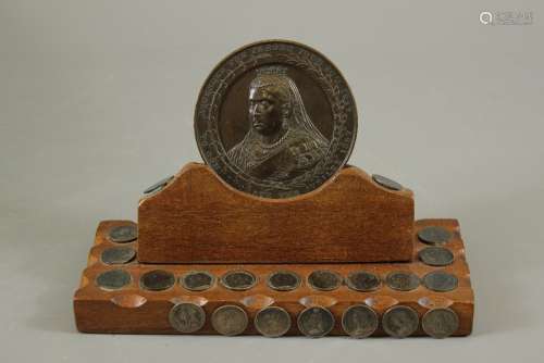 A Queen Victoria Bronze Medallion, commemorating the Jubilee 1887, supported on an oak plinth mounted with a small collection of silver coins