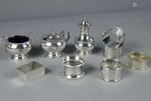A Silver Cruet, comprising pepper, salt, mustard, complete with blue liners, Sheffield hallmark, dated 1915, mm Walker & Hall together with six silver napkin rings, Birmingham hallmark, various dates, approx 294 gms