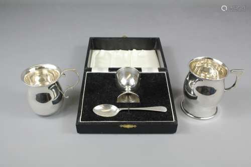 Two Silver Christening Mugs, the first Sheffield hallmarked dated 1922, mm HW, the second Chester hallmarked dated 1928, approx 178 gms together with a silver Christening boxed Egg Cup and Spoon, Birmingham hallmark, dated 1961