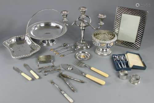 A Collection of Silver Plate, known manufacturers including Mappin & Webb, the lot comprises large twin-handled tray with scroll engraving, rose bowl, three branch candelabra,one swing-handled fruit basket,  three entree dishes, two boxes of cake forks, one box of tea knives, fish servers, nut crackers, knife rests, napkin rings, cigarette case, box of flatware for six places (four teaspoons missing)