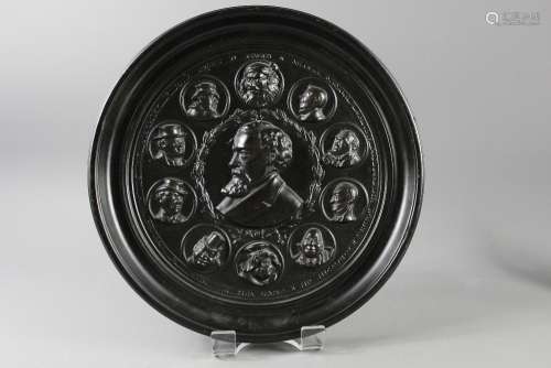 A Dickens Composite Ebony Plaque; the plaque depicting a profile of Charles Dickens in the centre, surrounded by various characters from his works, including 