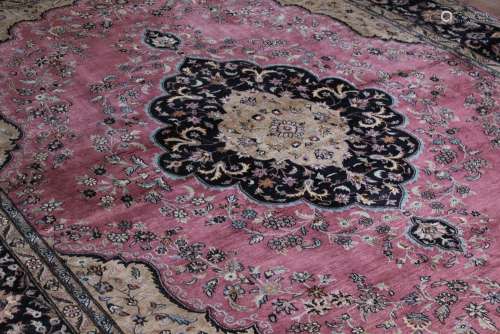 A Large Wool Carpet; the carpet has an overall floral motif, navy blue central medallion set on a crushed raspberry and beige background with blue highlights