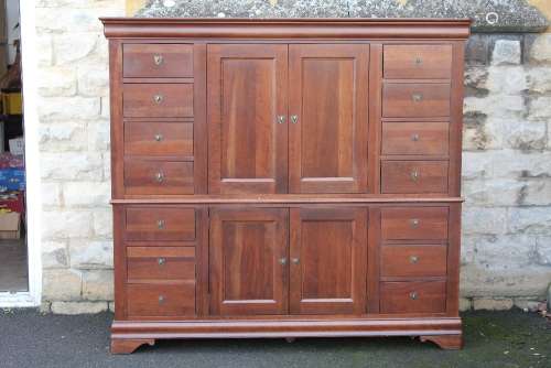 A Canadian Denham Compactum; the compactum comprising seven drawers on either side of a central cupboard with shelf, a further cupboard beneath, approx 183 x 60 x 167 cms, on bracket feet