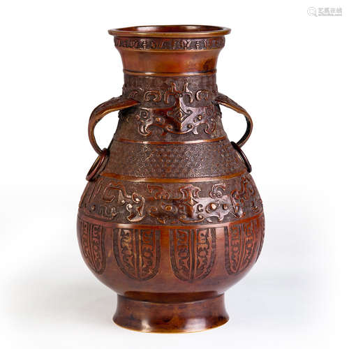 A CARVED COPPER VASE WITH TWO EARS