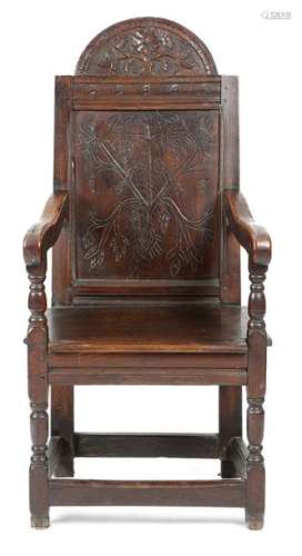 An oak panelled back armchair, the arched top carv…