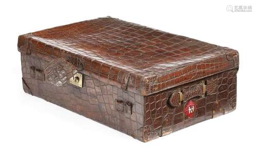 A large crocodile leather suitcase, the hinged lid…