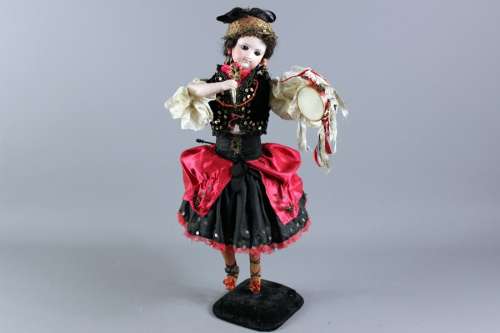Antique Automaton Gypsy Rose, the bisque headed doll with brown glass eyes and painted features, porcelain arms and legs, wearing a cream cotton blouse with a black velvet bolero heightened with sequins and a black skirt with pink overskirt heightened with sequins