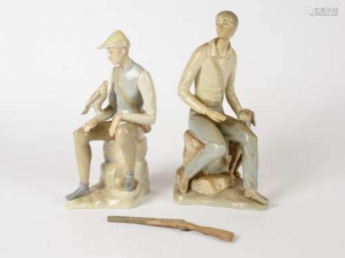 Two Spanish porcelain figures, both seated, one with gun dog, the other with bird of prey, height of