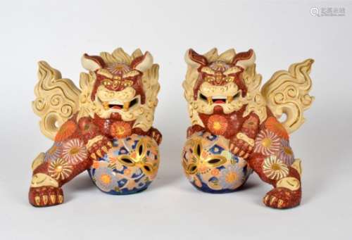 A pair of contemporary Chinese pottery figures of dogs of fo, on blue and gilt pierced balls, 25cm