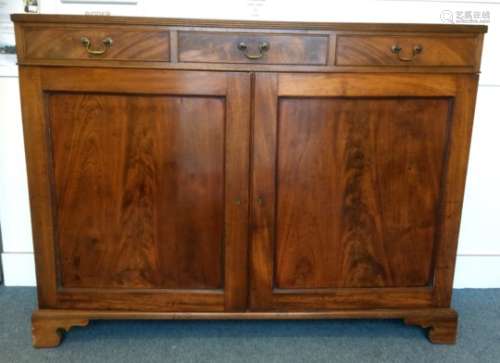An antique mahogany side cabinet, with three single drawers above two panelled doors and a reeded