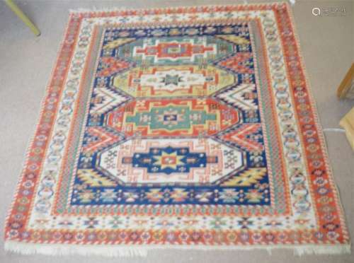 A Kazak rug, with four central medallions on a navy ground, bordered with with red, cream and