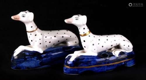 A pair of Staffordshire pottery ‘long dog’ Dalmatian pen stands, each modelled lying on a blue