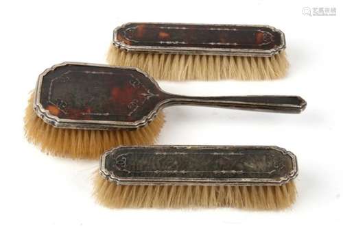 Three silver and tortoiseshell brushes.