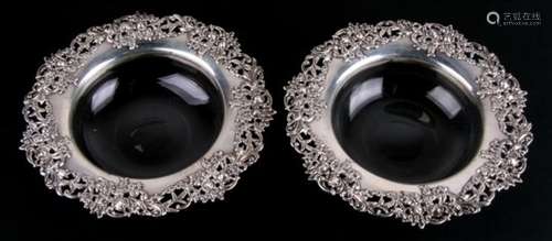 A pair of American sterling silver and glass bottle coasters, with ornate cast and pierced floral