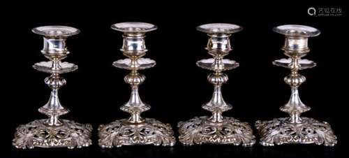 A set of four silver plated candlesticks with ornate pierced bases and dished drip pans below