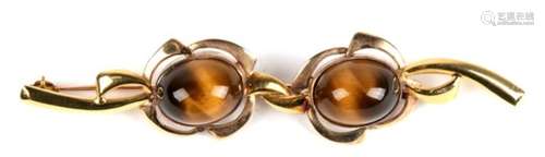 A large brooch of both 9ct and 18ct gold, set with two cabochon tiger eye stones. Possibly a pair of