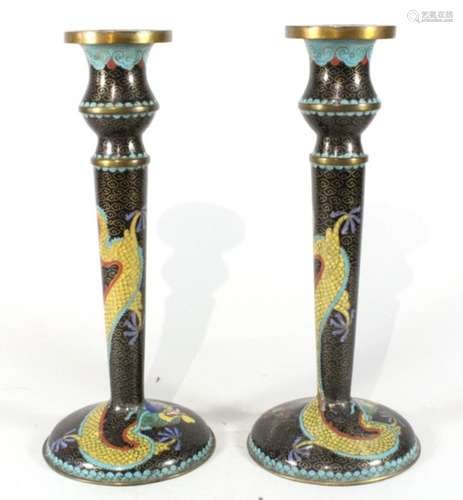 A pair of Chinese cloisonne candlesticks decorated dragons on a black ground