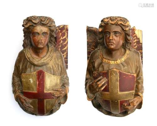 A pair of wall mounted carved and painted wooden corbels in the form of angels, each holding a