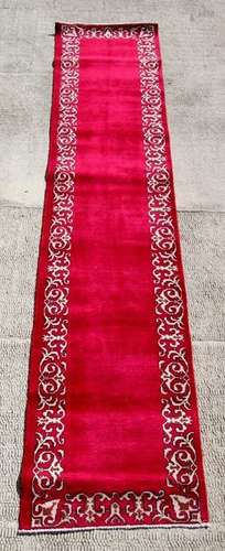 A Persian Tabriz woollen hand knotted runner with stylised borders on a claret ground, 380 by