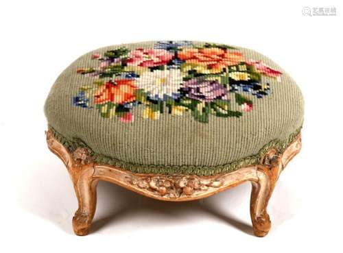 A distressed painted footstool with needlepoint upholstery, 37cms (14.5ins) diameter.