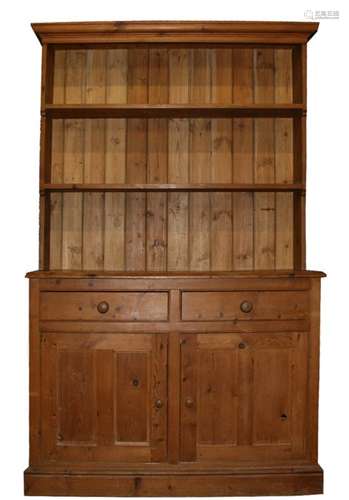 A pine dresser with a two shelf rack above two short drawers and cupboard beneath, on a plinth base,