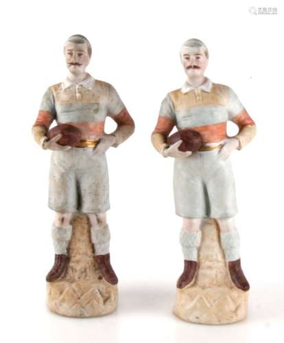 A pair of Victorian bisque porcelain rugby players dressed in kit and holding a bowl, 20cms (8ins)