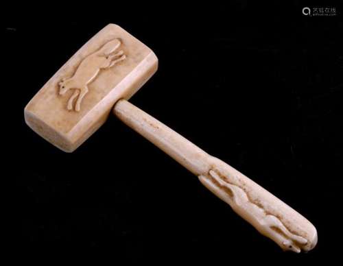 An Inuit marine ivory mallet carved with an arctic hare and foxes, 20cms (8ins) long.