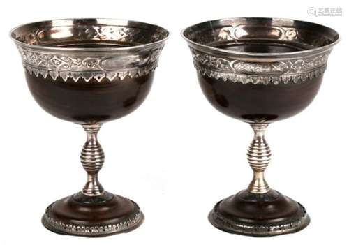 A pair of silver mounted lignum vitae loving cups in the form of chalices. The rim and foot rim