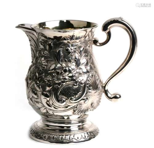 A George II silver beer jug with later embossed floral decoration and armorial crest to the