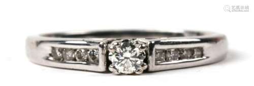 An 18ct white gold and 0.25ct diamond ring, 4 small stones to each shoulder flanking a larger