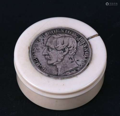 A 19th century circular ivory box, the lid set with an 1861 Hanover Thaler coin. 5cm (2 ins)