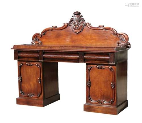 A Victorian mahogany pedestal sideboard with carved crest rail above three cushion frieze drawers