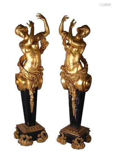 A pair of carved and giltwood caryatid figures of life size naked form, on black painted columns