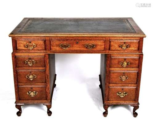 An early 20th century oak pedestal desk with an arrangement of nine drawers, on dwarf cabriole legs,