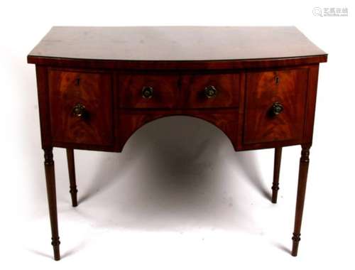 A mahogany bow fronted sideboard with central frieze drawer flanked by cupboards, standing on turned