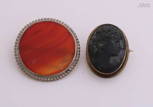 Two brooches, a white metal brooch with a round stripe
