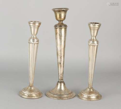Three silver candlesticks, a big candle on round base
