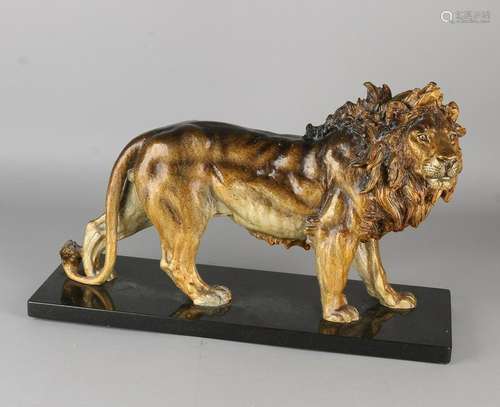 Large metal lion with polychrome. On black marble base.