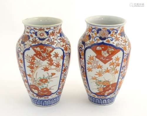 A pair of Imari vases with panelled floral decoration, with stylised trees and flowers. Approx.