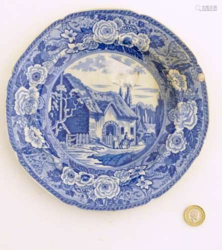 A 19thC blue and white transferware plate depicting a country scene with a thatched cottage,