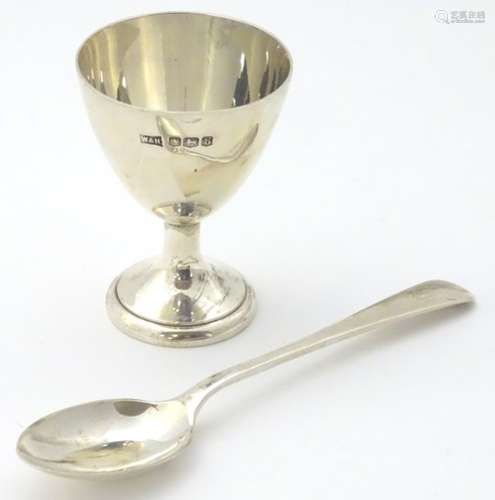 A silver pedestal egg cup together with a spoon.