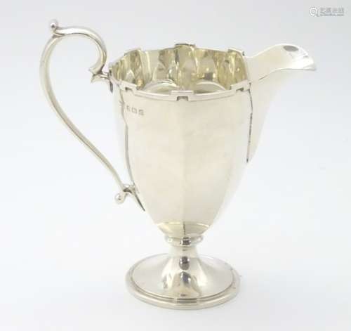 A silver cream jug with castellated rim,