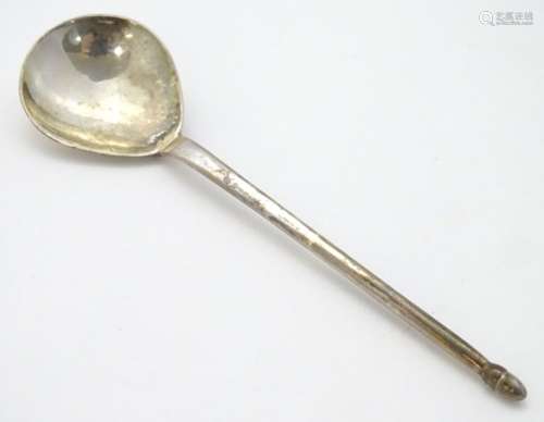 A silver spoon with hammered bowl and acorn finial.