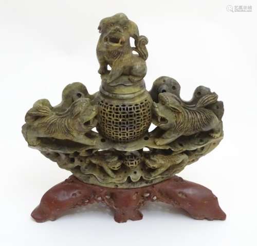 A 19thC Asian carved soapstone reticulated lidded bowl, flanked by foo dogs,